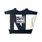 Tote bag with black and white design and 'Playwear Remade in Nova Scotia' logo on a white background